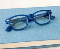 Blue reading glasses on a blue surface