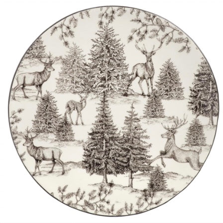 A round ceramic plate featuring a pattern with reindeer and pine trees on an off-white background.