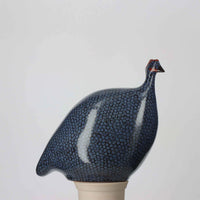 Ceramic sculpture of a Guinea fowl with a blue body on a white background