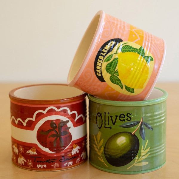 Three decorative vases with fruit-themed designs on a wooden surface.