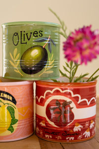 Three colorful ceramic vases with illustrations of olives, lemons, and a tomato on a wooden surface.