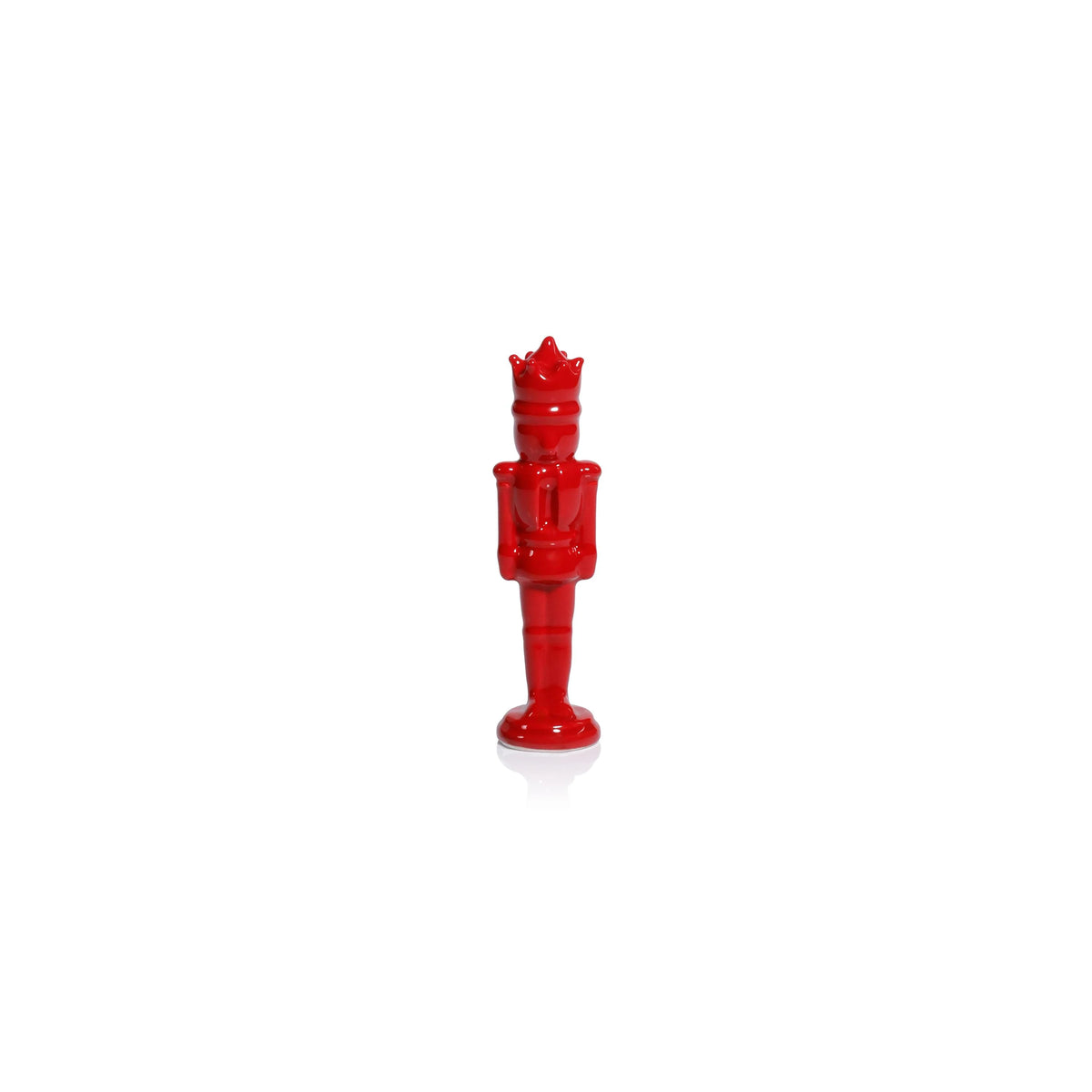 A glossy red nutcracker figurine standing upright on a white reflective surface against a white background.