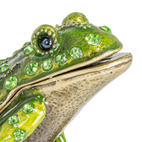 Decorative frog figurine with green gemstones on a white background