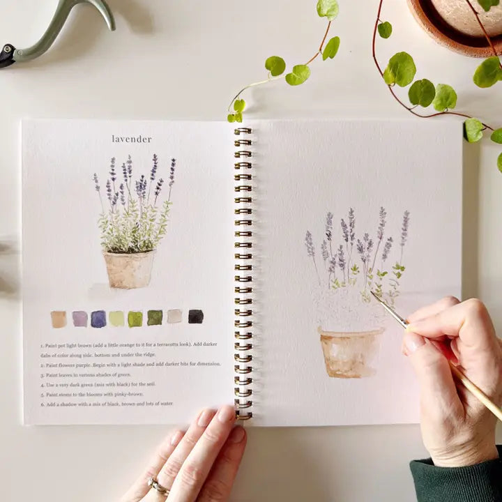 Person painting lavender in a sketchbook with color swatches