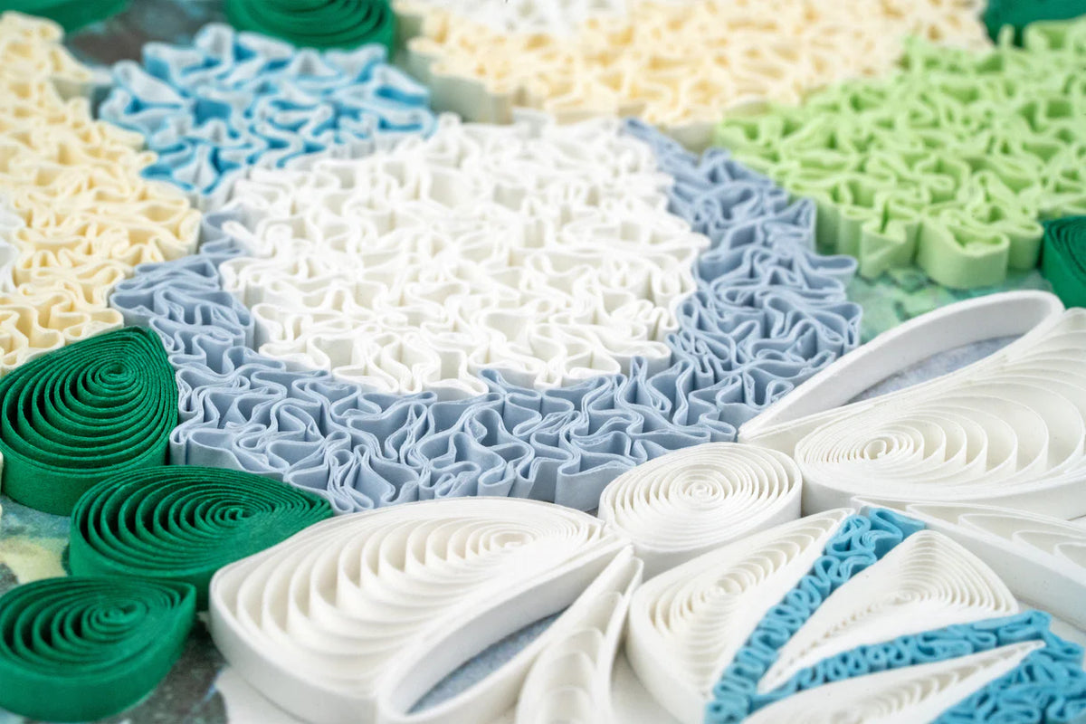 Close up of colorful paper quilling with blue, green, and white patterns.