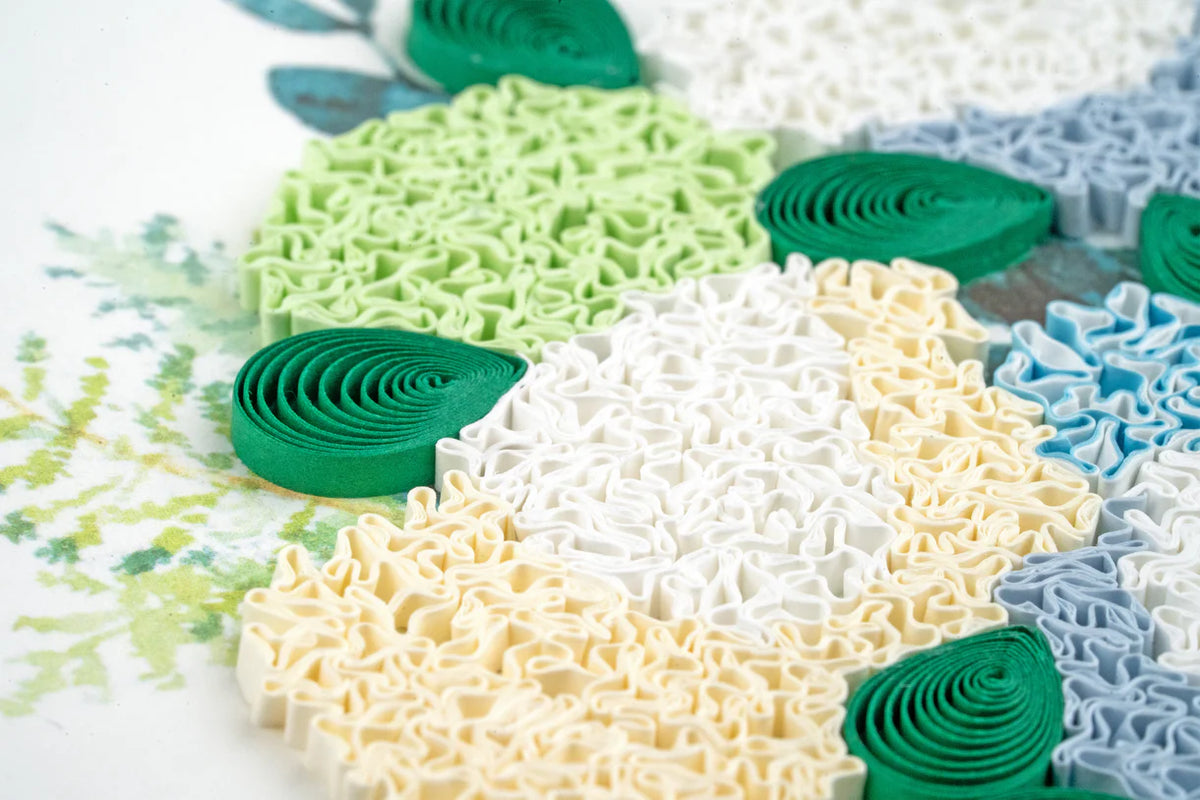 Close up of colorful quilled paper flower petals and leaves on a white background