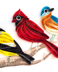 Quilled paper birds in red, blue, orange, and yellow on a white background.