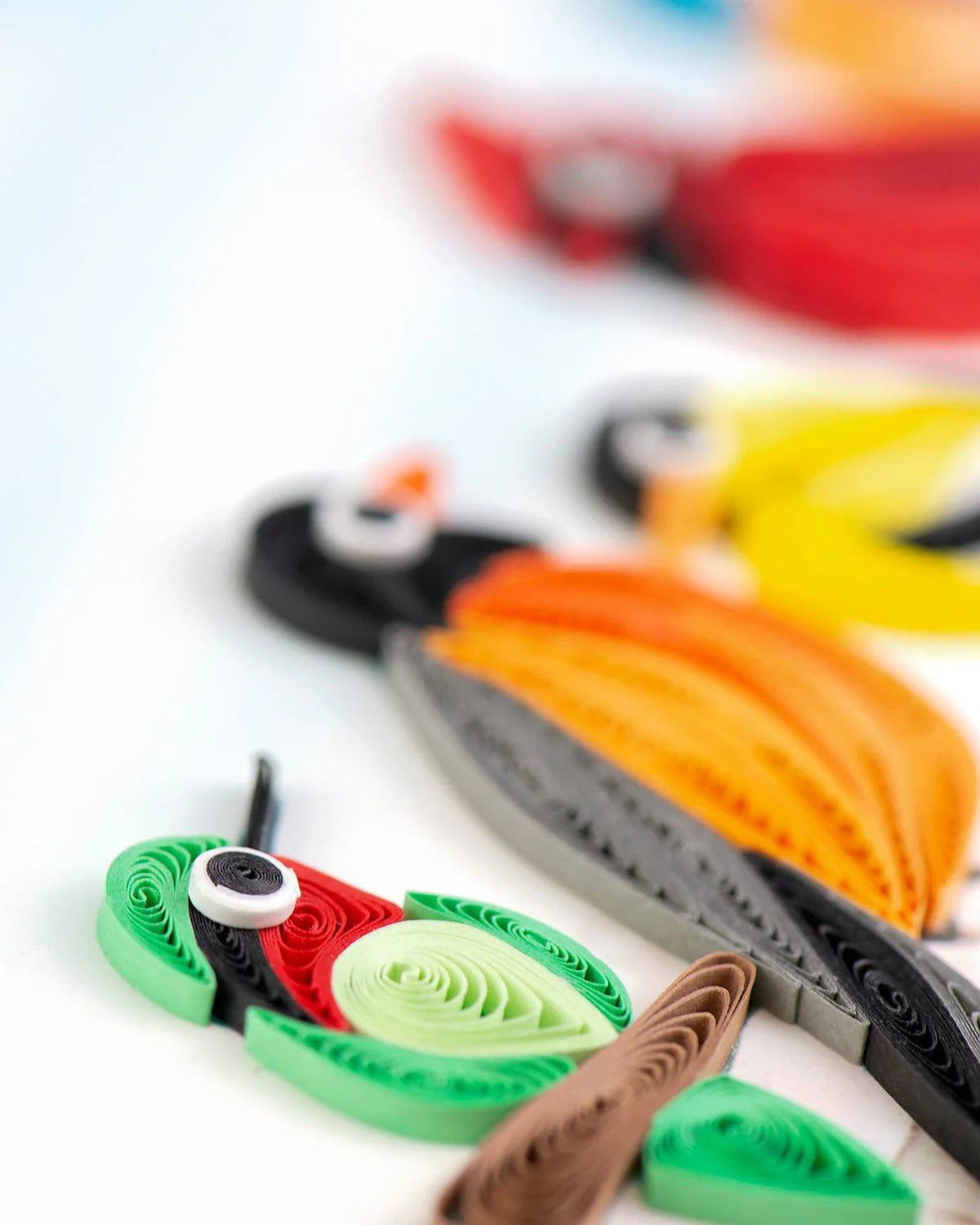Colorful paper quilled bird figures on a white background