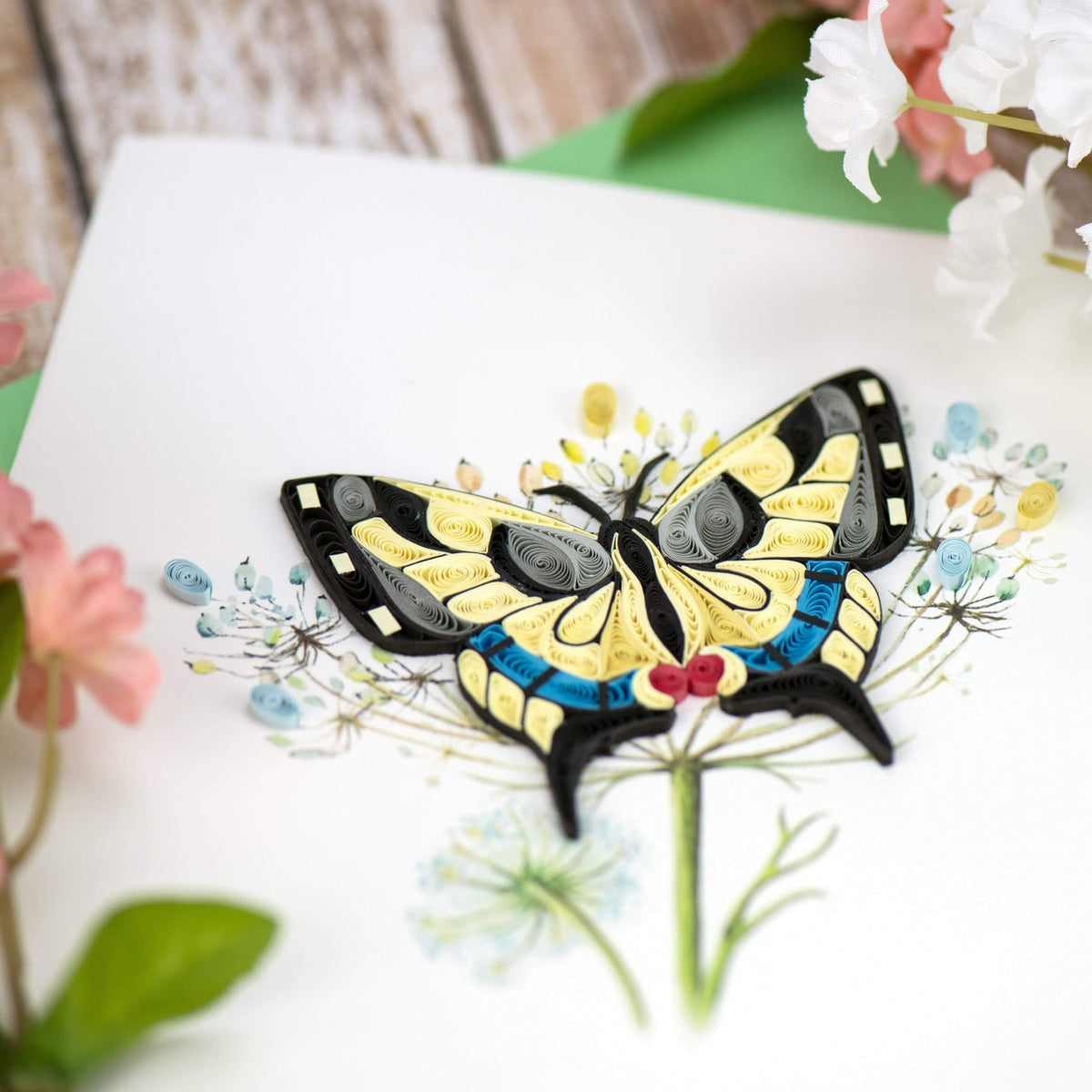 Colorful quilled swallowtail butterfly greeting card on a white background with flowers.