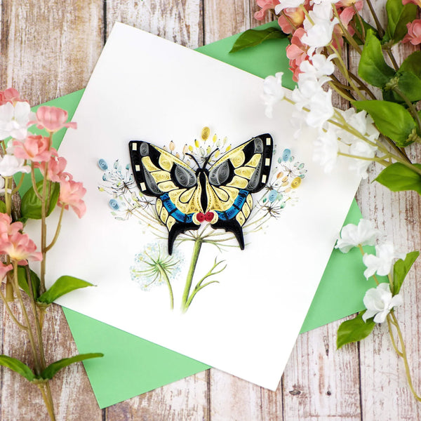 Quilled butterfly greeting card with flowers on a wooden background
