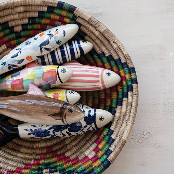 Colorful ceramic fish figurines in a woven basket on a light surface