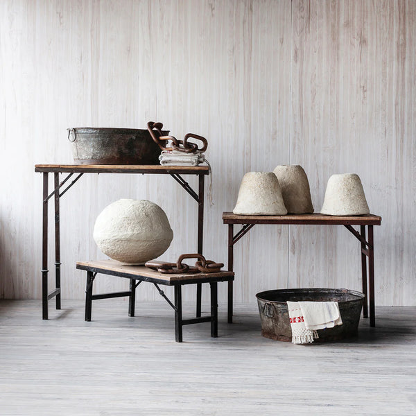 Vintage-style room with wooden tables and rustic decor against a light wooden paneled wall.