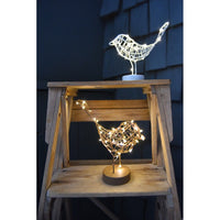 Decorative bird-shaped lights on a wooden stand against a dark background