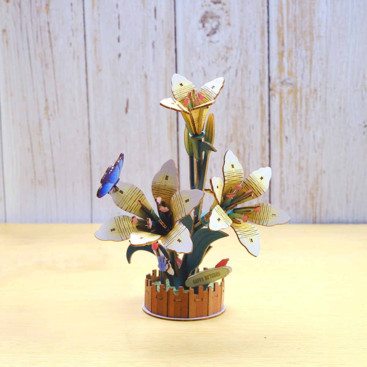 3D wooden flower sculpture with butterflies on a wooden surface and light wood panel background