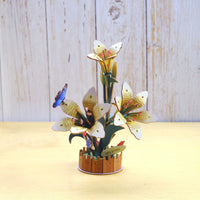 3D wooden flower sculpture with butterflies on a wooden surface and light wood panel background