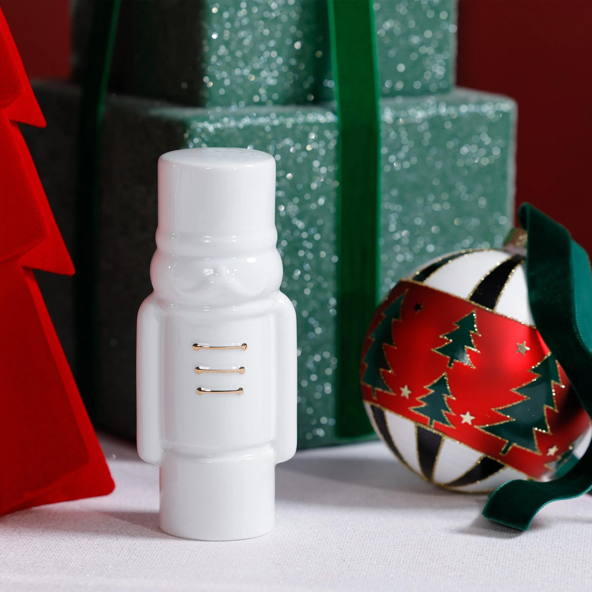 White soldier figurine with gold accents on a snowy surface with Christmas decorations.