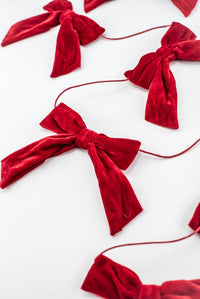 Red velvet bow garland on a white background.