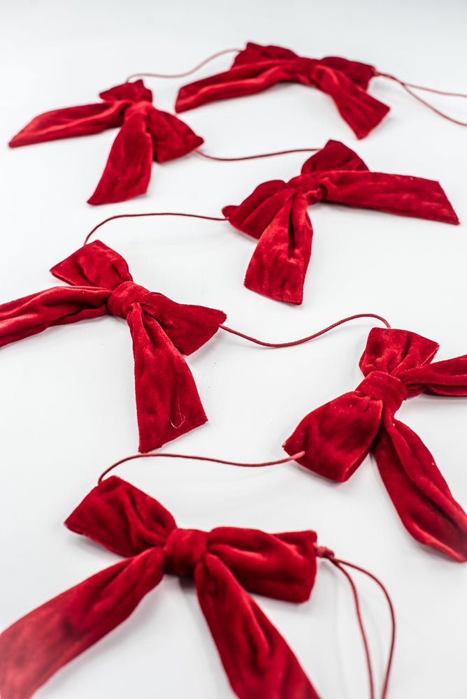 Red velvet bow garland draped diagonally on a clean white background.