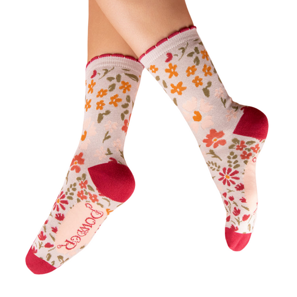 Floral patterned socks with red toes and heels worn by a person on a white background