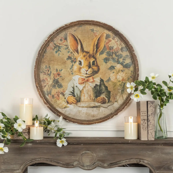 Decorative wall piece with a rabbit illustration on a wooden shelf with candles and flowers.
