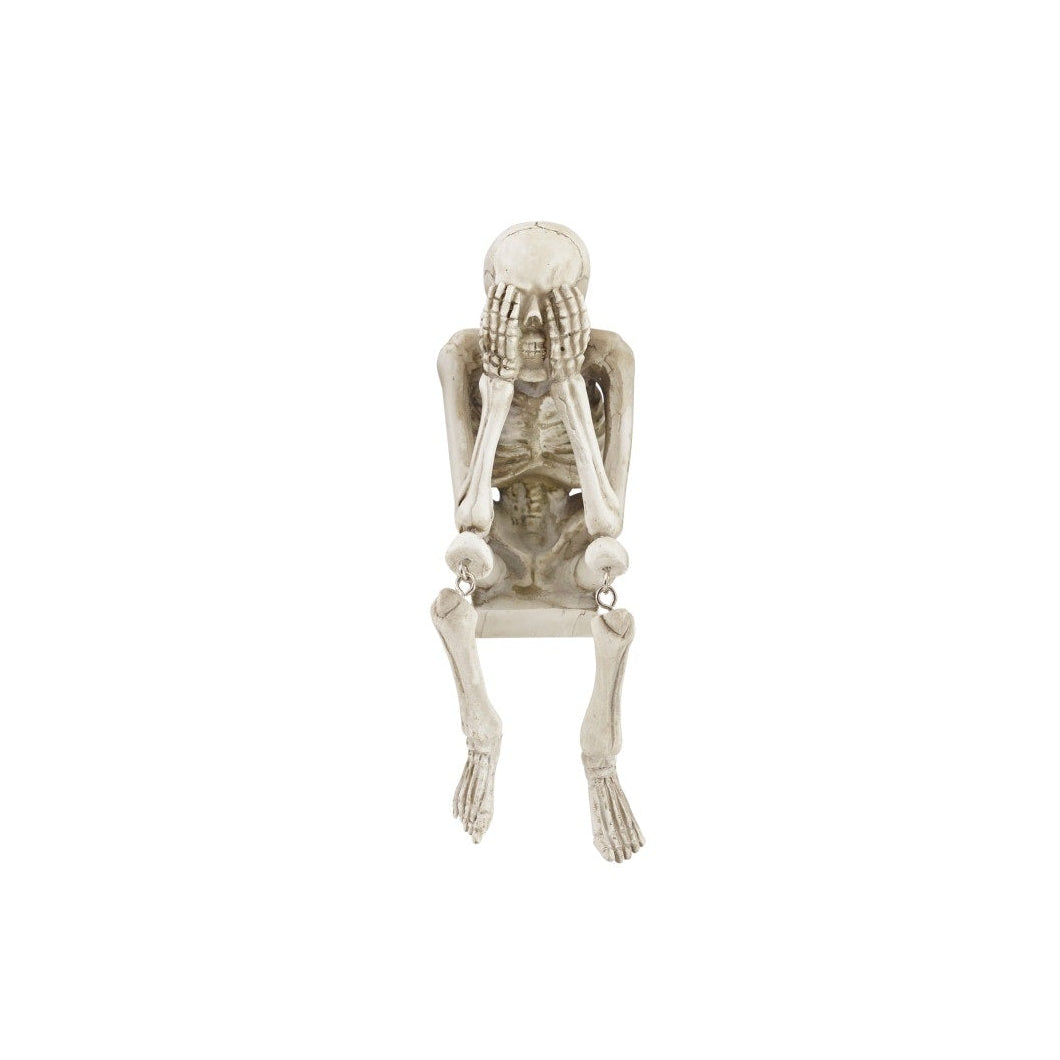 A decorative skeleton shelf sitter with its hands over its mouth in a 'see no evil' pose on a white background.