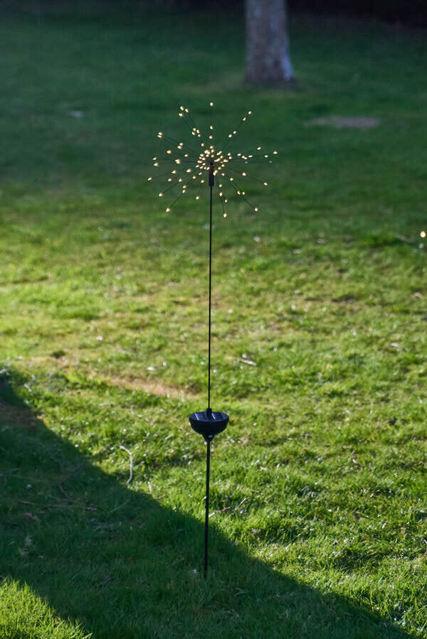 Solar garden light on grass with tree in background