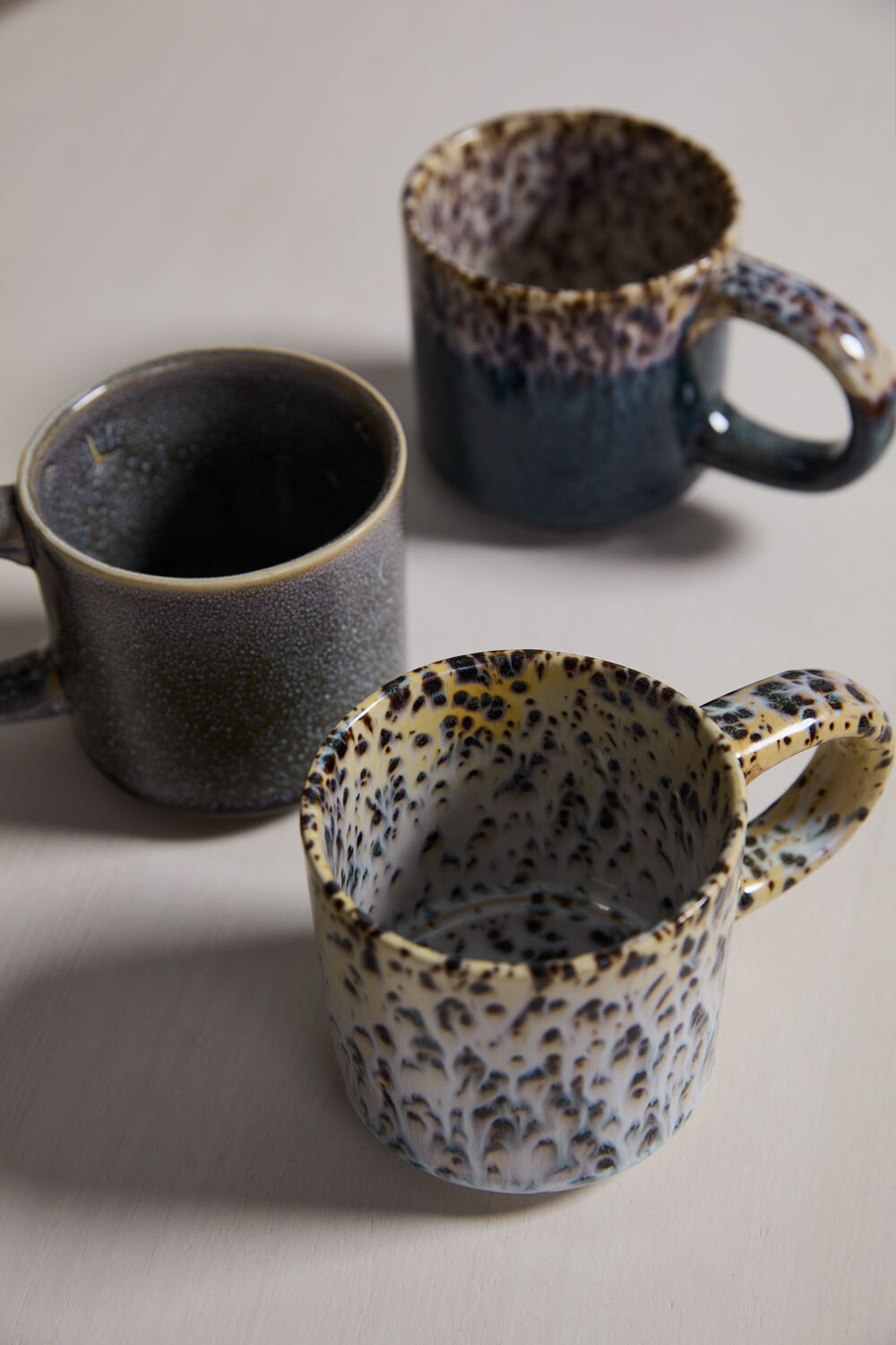 Three ceramic mugs with different print patterns on a light background