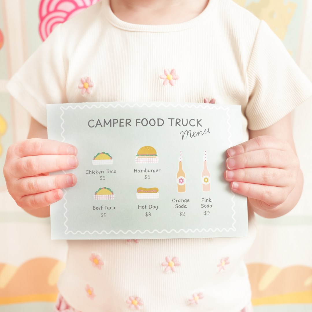 Child holding a 'Camper Food Truck Menu' with illustrations and prices.