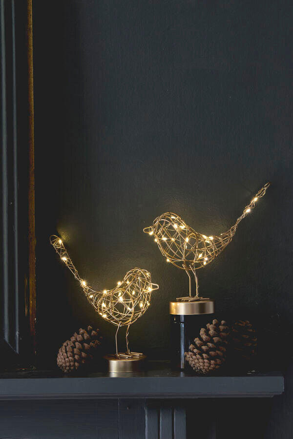 Two wire bird sculptures with string lights on a dark background