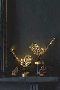 Two wire bird sculptures with string lights on a dark background