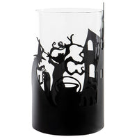 A black cylindrical candle holder or vase with a Halloween-themed silhouette cutout design featuring a witch, cat, cauldron, and haunted house, shown against a plain white background.